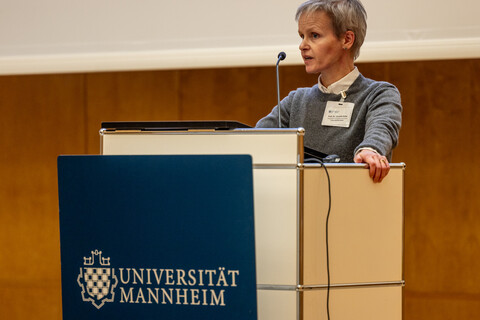 Prof. Dr. Cornelia Ruhe steht an einem Renderpult und spricht e 