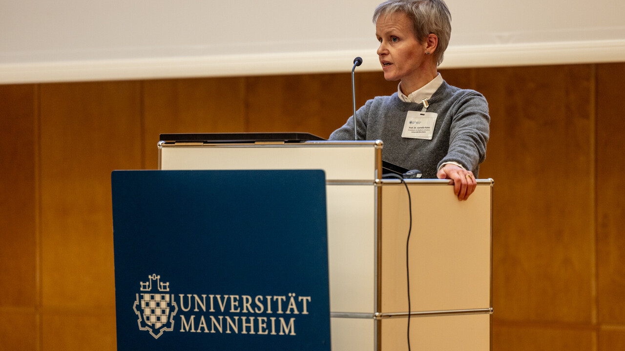 Prof. Dr. Cornelia Ruhe steht an einem Renderpult und spricht e