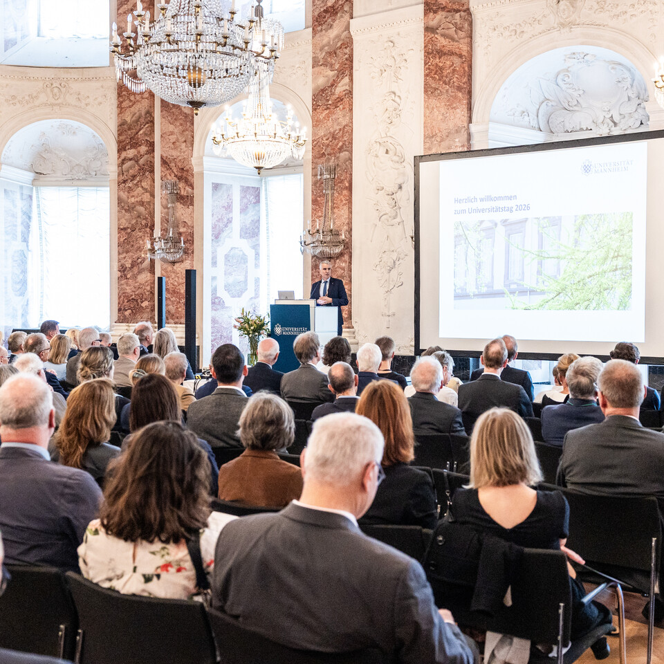 Blick in den vollbesetzten Rittersaal. Auf der Bühne ist eine Präsentation zu sehen und der Rektor am Rednerpult.