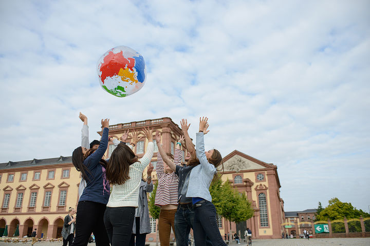 Eine Gruppe von Studierenden wirft im Ehrenhof eine aufgeblasene Weltkugel in die Luft.