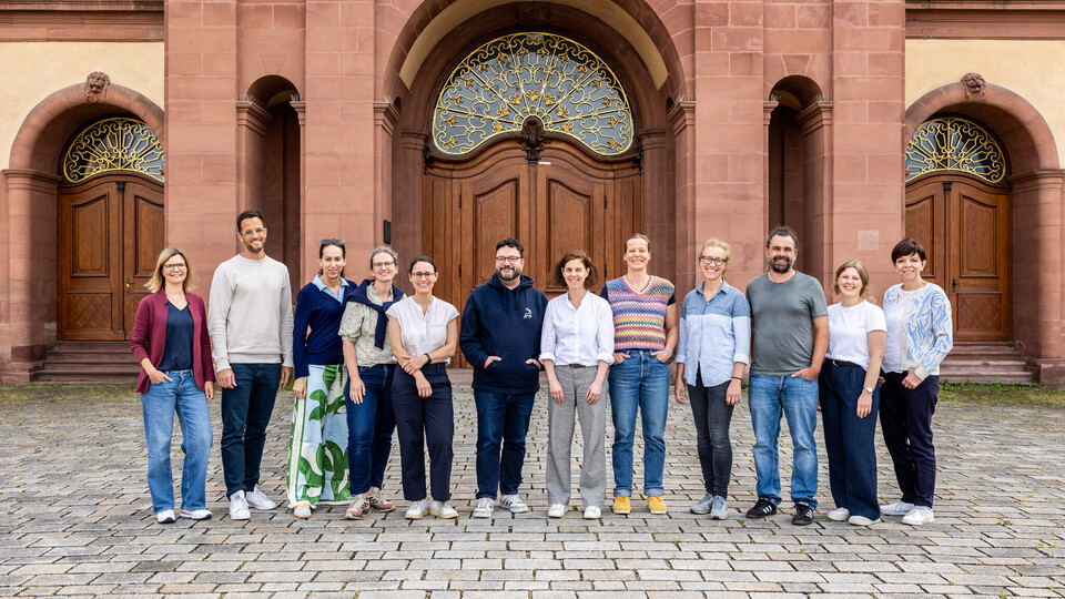 Eine Gruppe steht nebeneinander vor dem Schloss Mannheim.