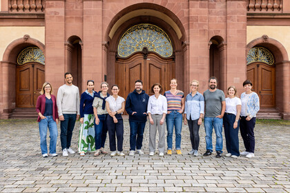 Eine Gruppe steht nebeneinander vor dem Schloss Mannheim.