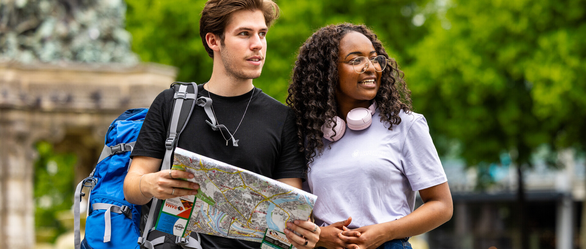 Zwei gutgelaunte Studierende mit einem Stadtplan in der Hand.