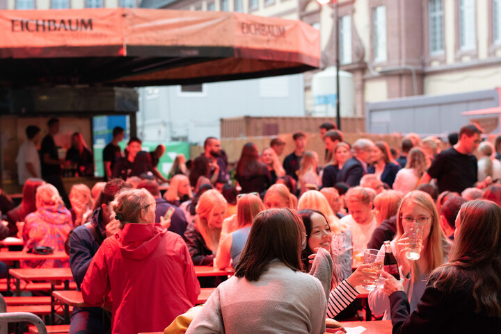 Viele Menschen sitzen zusammen und essen und trinken.