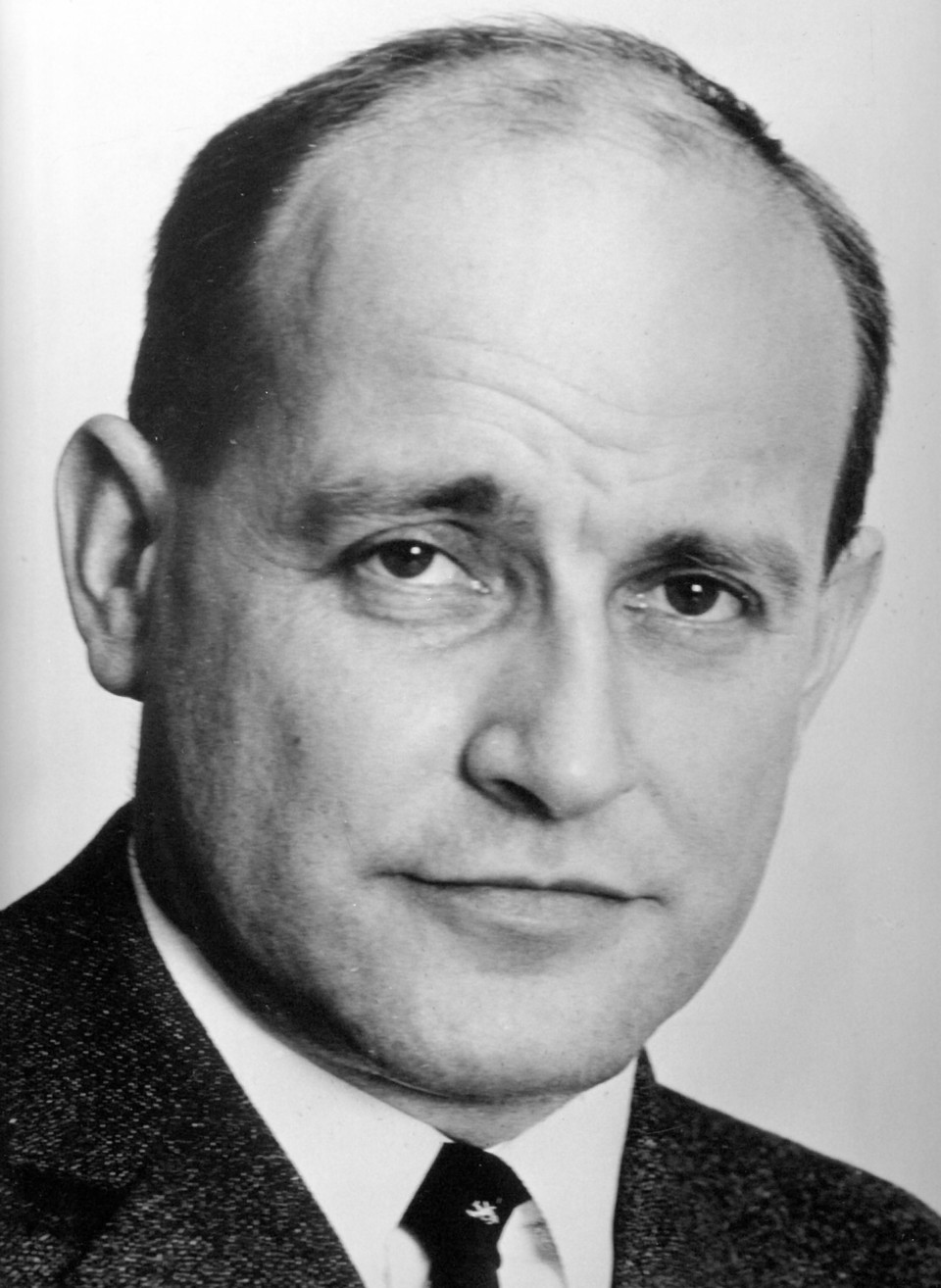 Schwarz-weiß Portrait von Knut Borchardt. Er trägt ein weißes Hemd, eine dunkle Krawatte sowie einen dunklen Blazer.