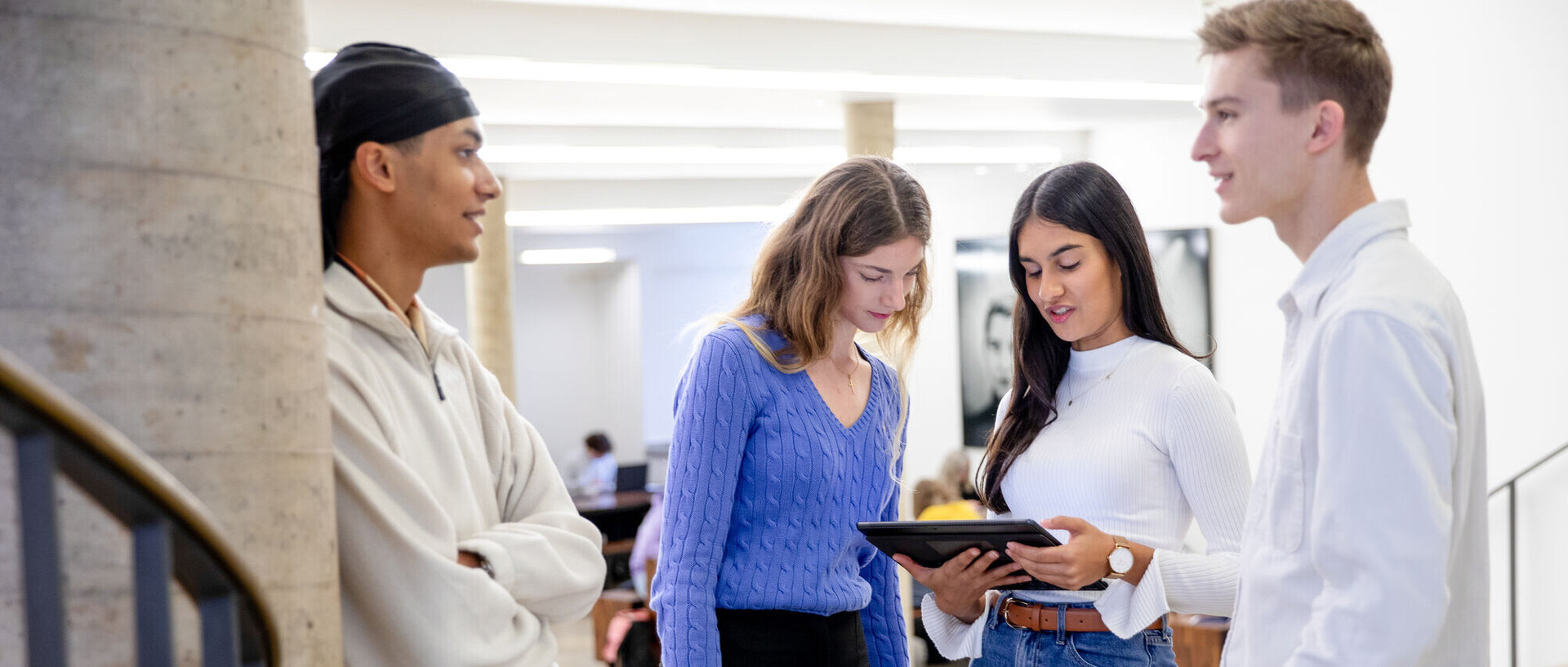 Application for Bachelor's Programs Zwei Studenten und zwei Studentinnen stehen zusammen und betrachten etwas auf einem Tablet.