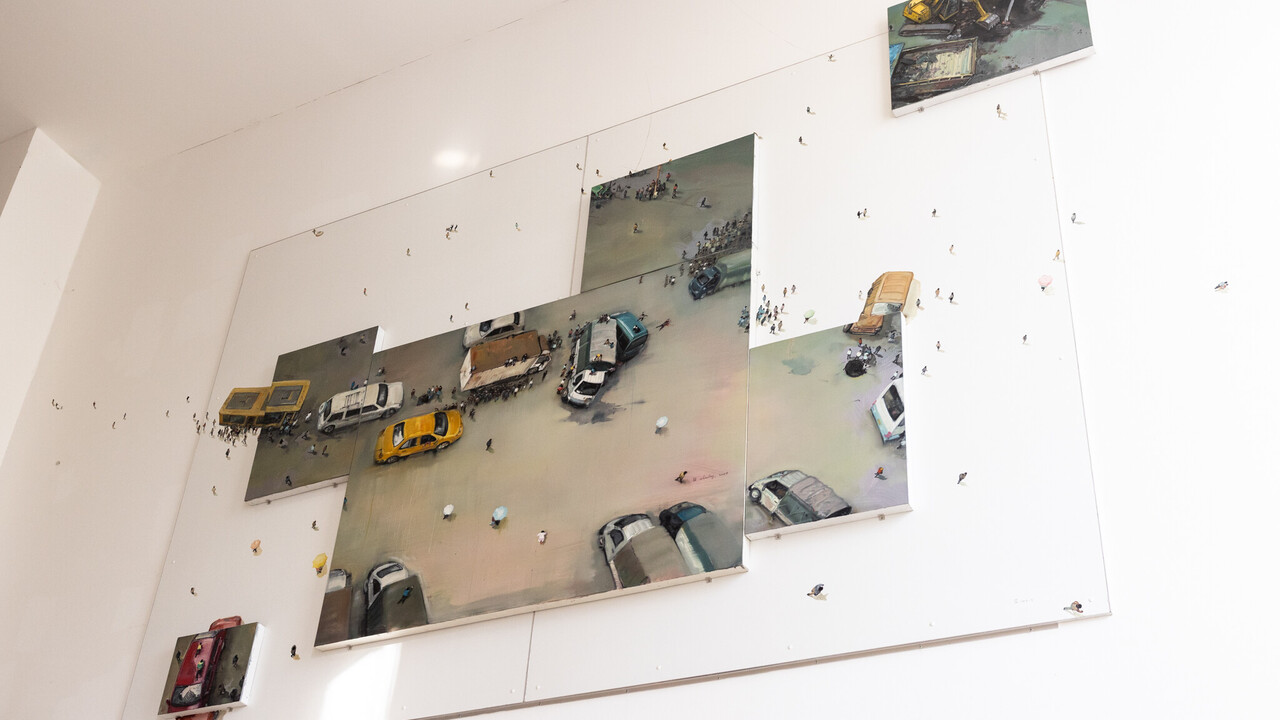 Kunstwerk mit gemalten Autos und kleinen Figuren an der Wand.