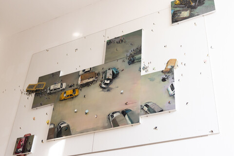 Kunstwerk mit gemalten Autos und kleinen Figuren an der Wand.