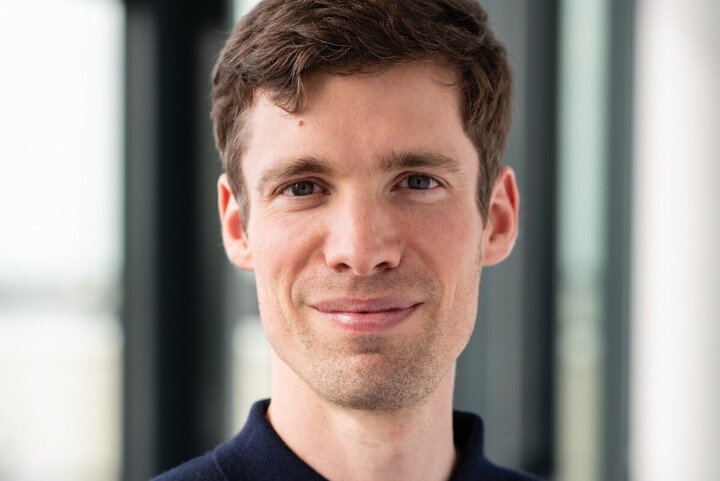 Alumnus Matthias Haller hat kurze braune Haare, trägt ein dunkelblaues Hemd und lächelt