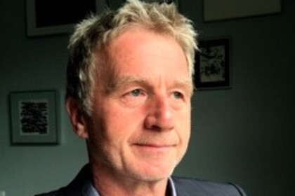 Portrait von Thomas König. Er trägt ein hellblaues Hemd sowie einen grauen Blazer.