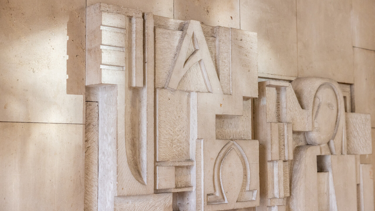 Kunstwerk mit Kopf in einer Steinmauer eingemeißelt