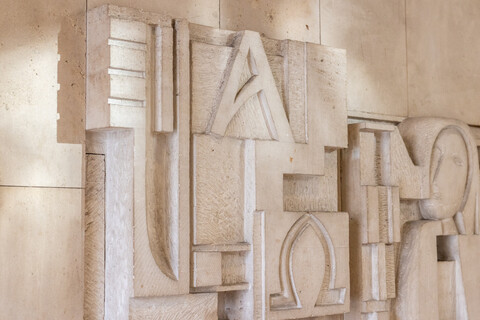 Kunstwerk mit Kopf in einer Steinmauer eingemeißelt