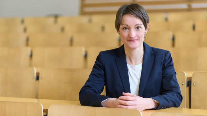 Tabea Bucher-Koenen sitzt in einem leeren Hörsaal auf einem Stuhl.