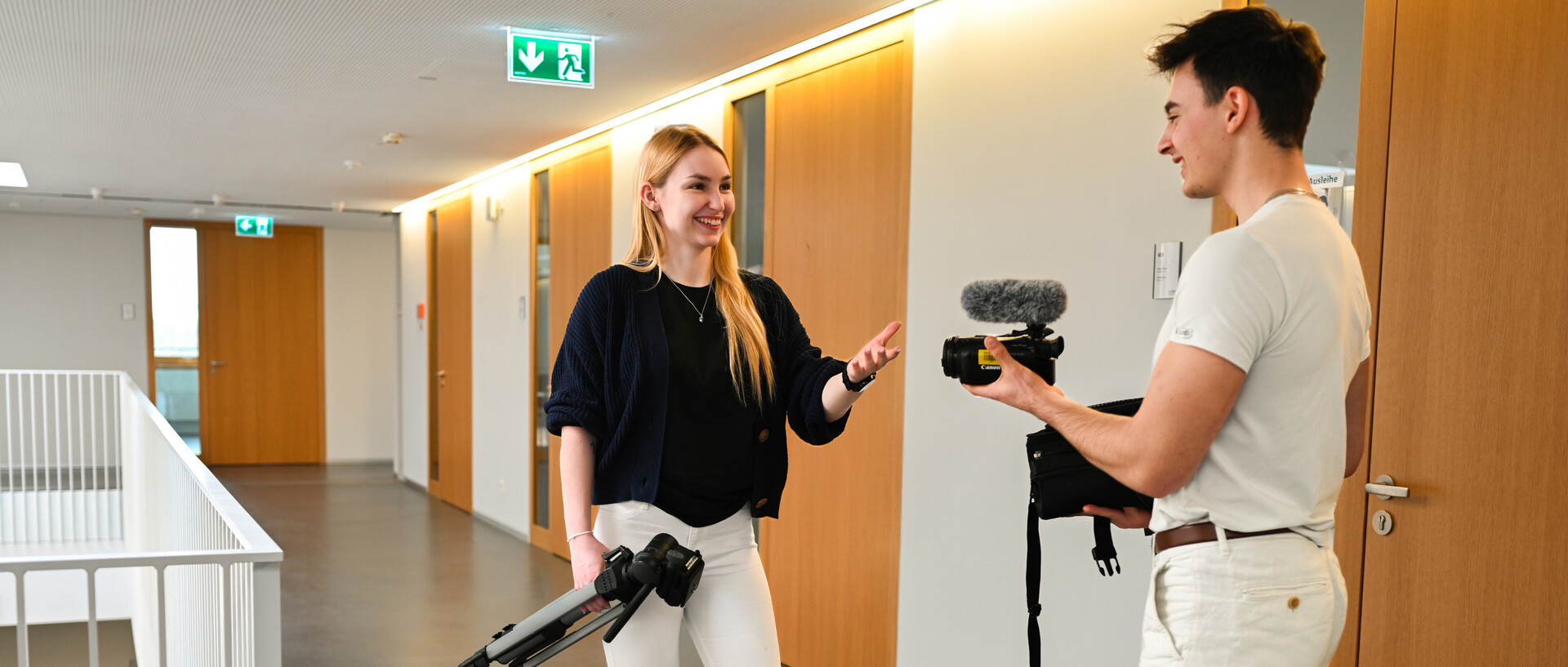 Zwei Studierende mit Kamera, Stativ und Mikrofon.