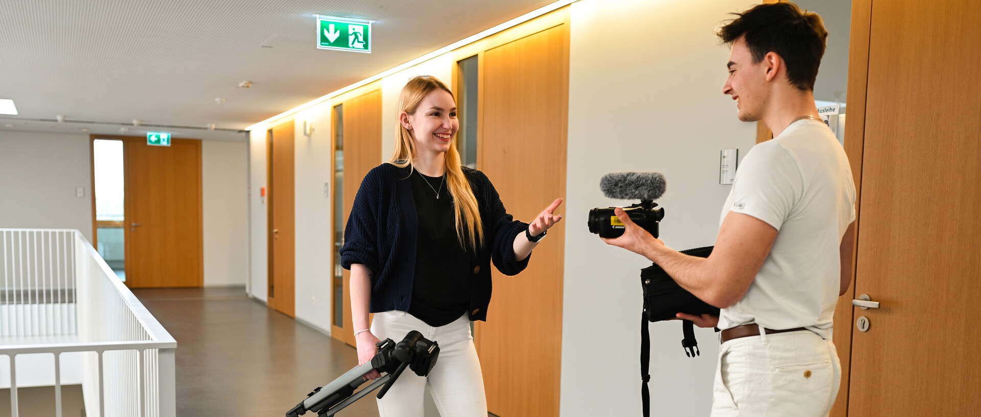 Zwei Studierende mit Kamera, Stativ und Mikrofon.