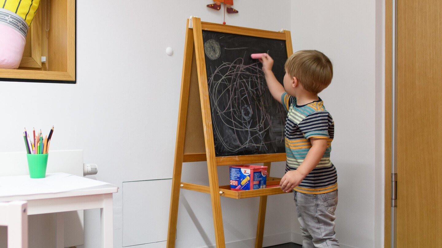 Foto eines Kindes das an die Tafel malt in einem Kinderzimmer.