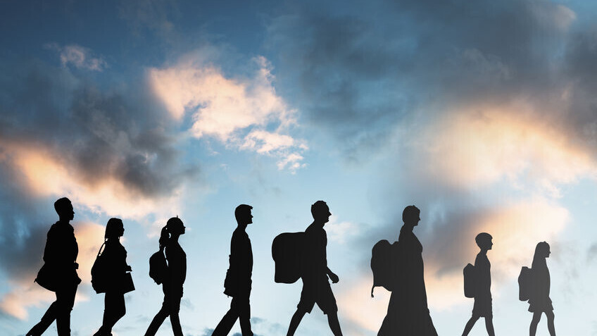 Eine Gruppe von Personen mit Gepäck läuft hintereinander nach rechts. Zu erkennen sind nur ihre wchwarze Silhouetten. Der Himmel ist wolkig.