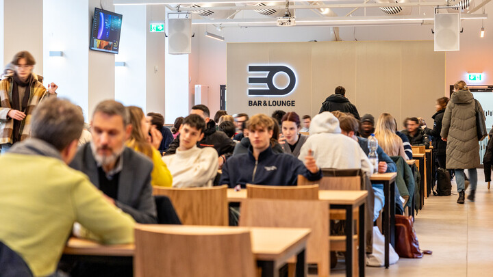 Studierende sitzen an modernen Holztischen in der EO Bar&Lounge.