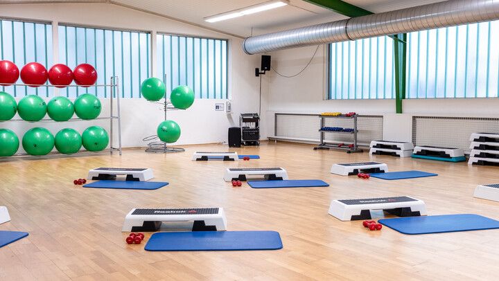 Sporthallte mit Steppern, Yogamatten und Hanteln zum Training bereit