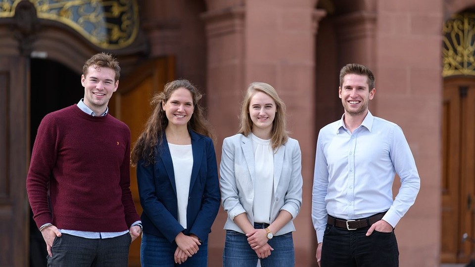 Vier Studierende stehen vor einem Eingang der Universität Mannheim.