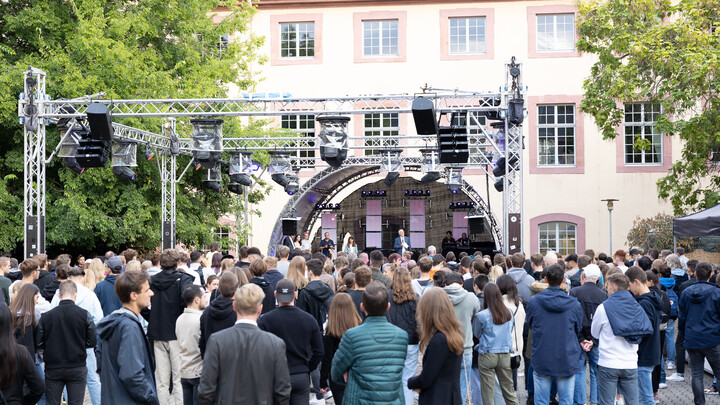 Der ehemalige Rektor der Universität Mannheim, Prof. Dr. Puhl, steht auf einer Bühne im Schneckenhof und begrüßt zahlreiche Erstsemester.