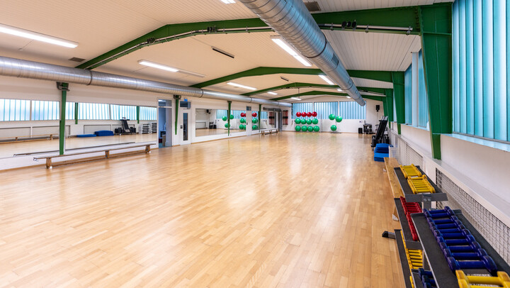 Innenansicht der Sporthalle mit Parkettoden und Trainingsgeräten