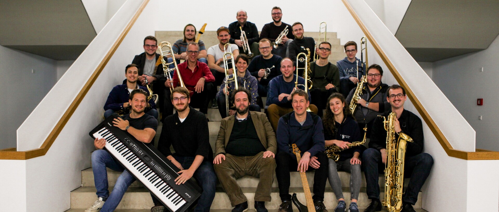 Mitglieder eines Orchesters sitzen mit ihren Instrumenten auf einer Treppe.