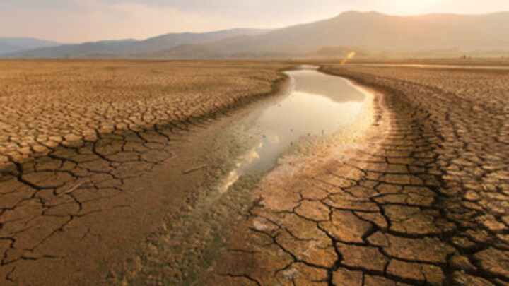 Ausgetrockneter See mit Wasserresten, drum herum Wüste. Die Sonne scheint.