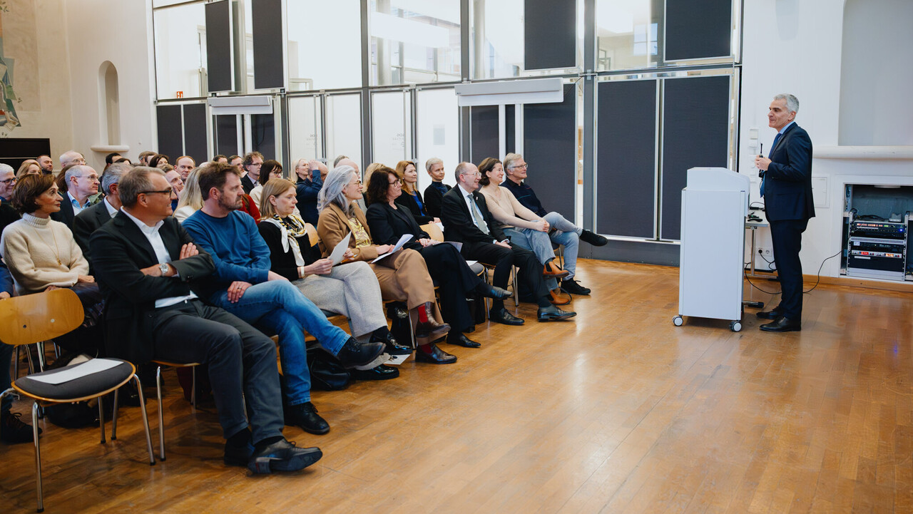 Der Rektor der Universität Mannheim steht an einem Rednerpult im Fuchs Festsaal. Der Saal ist vollbesetzt.