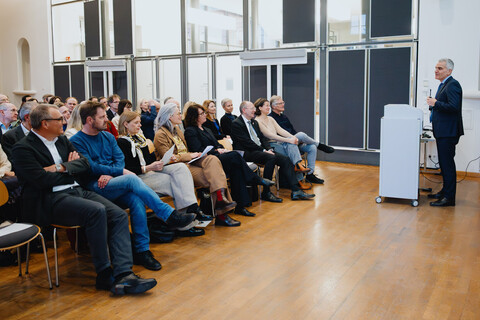 Der Rektor der Universität Mannheim steht an einem Rednerpult im Fuchs Festsaal. Der Saal ist vollbesetzt.