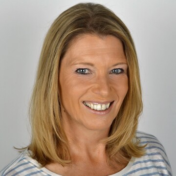 Porträt von Christiane Koch. Sie hat halblange blonde Haare, trägt ein gestreiftes Shirt und lächelt in die Kamera.
