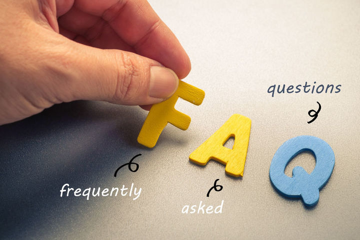 Eine Hand legt mit Buchstaben das Wort FAQ
