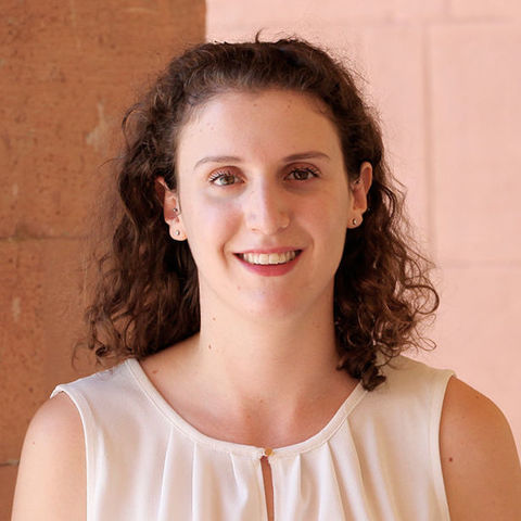 Silvia Brambilla has brown curly hair and a piercing in her ear. She is wearing a light-colored off-the-shoulder blouse.