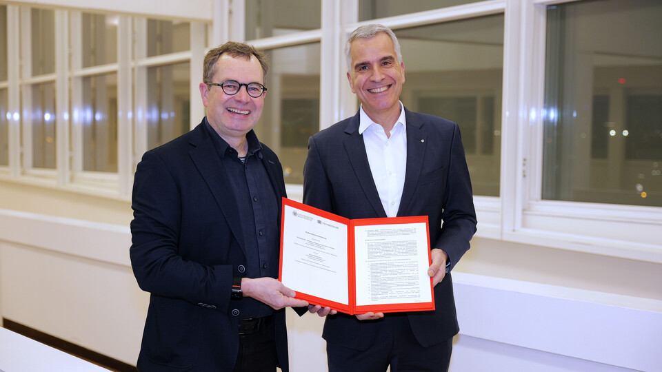 Prof. Dr. Thomas Fetzer und Prof. Dr. Andreas Gundelwein präsentieren lächelnd den Kooperationsvertrag zwischen der Universität Mannheim und dem Technoseum. 