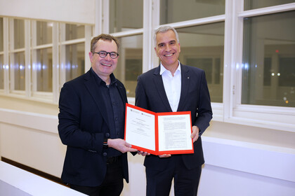 Prof. Dr. Thomas Fetzer und Prof. Dr. Andreas Gundelwein präsentieren lächelnd den Kooperationsvertrag zwischen der Universität Mannheim und dem Technoseum. 