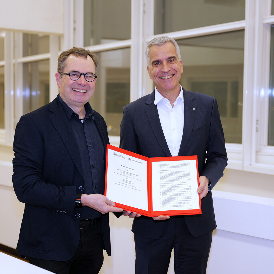 Prof. Dr. Thomas Fetzer und Prof. Dr. Andreas Gundelwein präsentieren lächelnd den Kooperationsvertrag zwischen der Universität Mannheim und dem Technoseum.