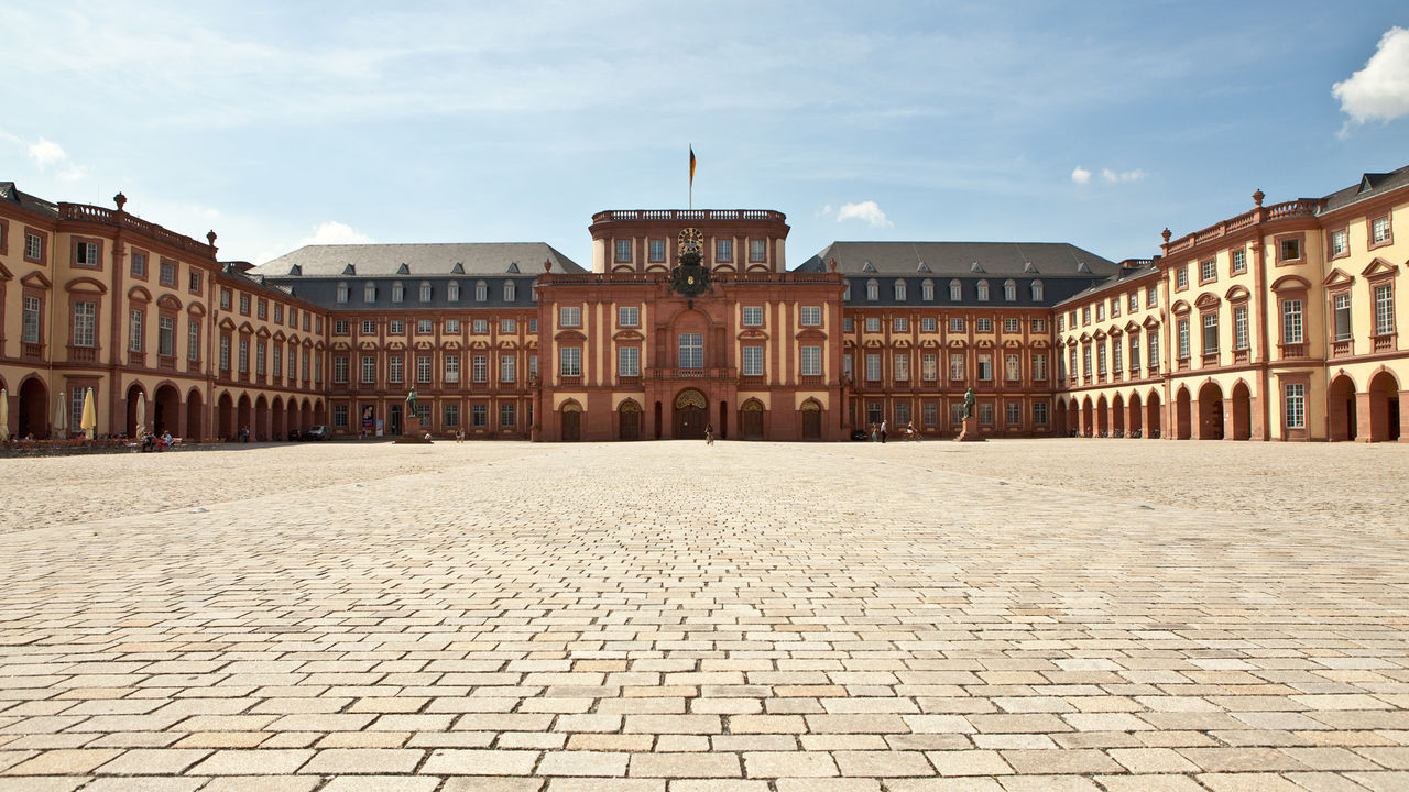 Das Mannheimer Barockschloss und der Ehrenhof bei blauem Himmel.