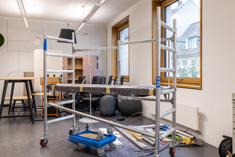 Das Foto zeigt eine Baustellen-Situation in einem Büroraum mit viel Werkzeug, das herumliegt und einem fahrbaren Gerüst