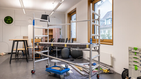 Das Foto zeigt eine Baustellen-Situation in einem Büroraum mit viel Werkzeug, das herumliegt und einem fahrbaren Gerüst