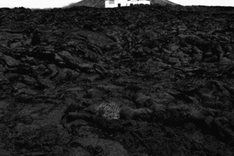 Schwarz-weiß Foto: Ein weißes Haus am Fuße eines Berges.