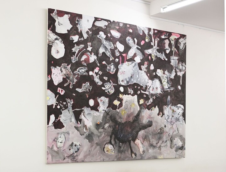 Die Aufenthaltsfläche im Schneckenhof Ost mit braunen Tischen und einem Bild an der Wand, das zahlreiche kleine und mittelgroße Wesen und Gegenstände zeigt