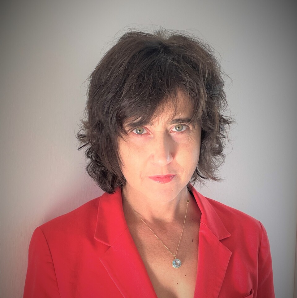 Irena Kogan trägt eine rote Bluse und schaut in die Kamera.