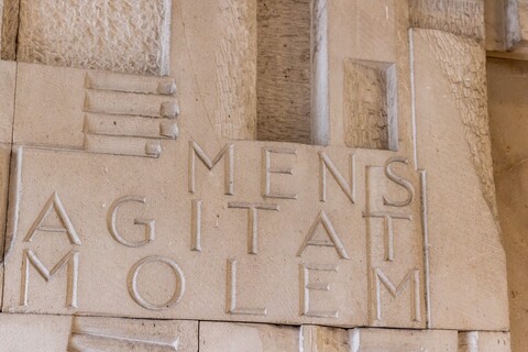 In eine Steinmauer ist der lateinische Ausdruck "Mens Agitat Molem" eingemeißelt.