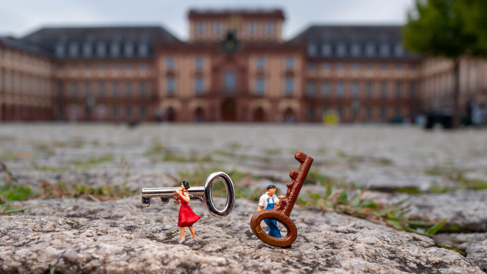 Kleine Menschen tragen große Schlüssel mit dem Schloss im Hintergrund