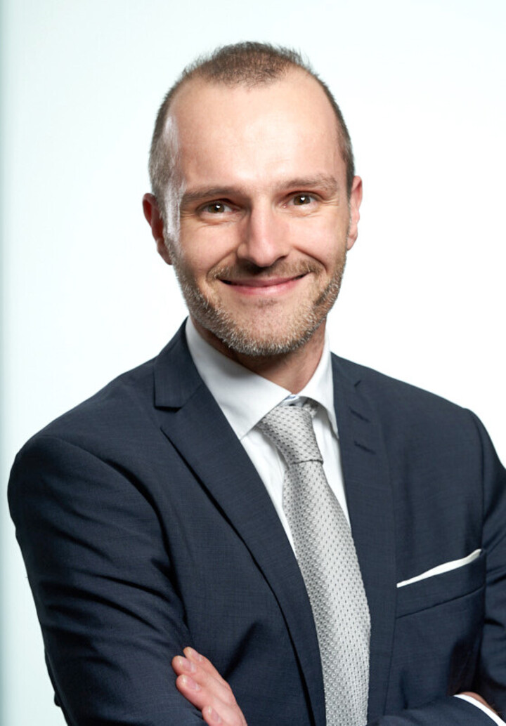 Portraitfoto eines Mannes in dunkelblauem Anzug.