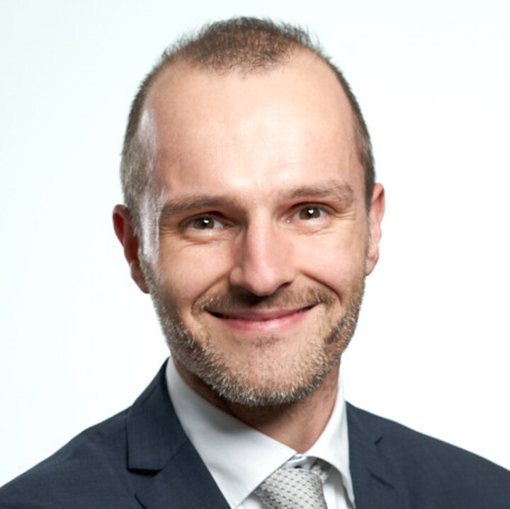 Portraitfoto eines Mannes in dunkelblauem Anzug.