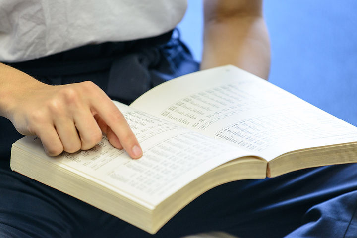 A student is pointing and reading a political science book on their lap.