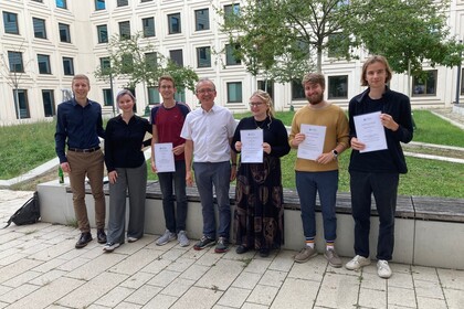 Six of the award winners and Thomas Gschwend are standing in the courtyard of B6, 30-32 and are holding their certificates.