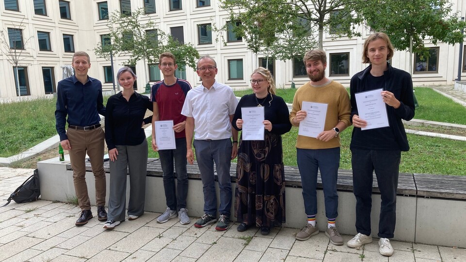 Six of the award winners and Thomas Gschwend are standing in the courtyard of B6, 30-32 and are holding their certificates.
