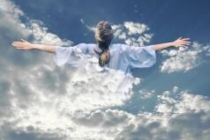 Eine Person in hellblauem Gewand im Himmel, die Arme ausgestreckt, verschmilzt mit den Wolken und schaut nach oben.